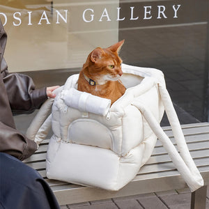 Abyssinian cat sitting comfortably in a stylish white quilted puffer pet carrier, perfect for travel and outings.