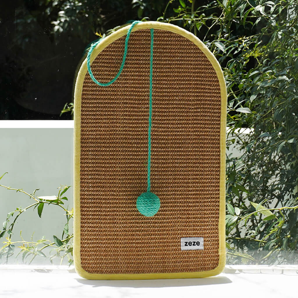 Dopamine-Style Cat Sisal Scratching Mat with green pom-pom displayed outdoors.