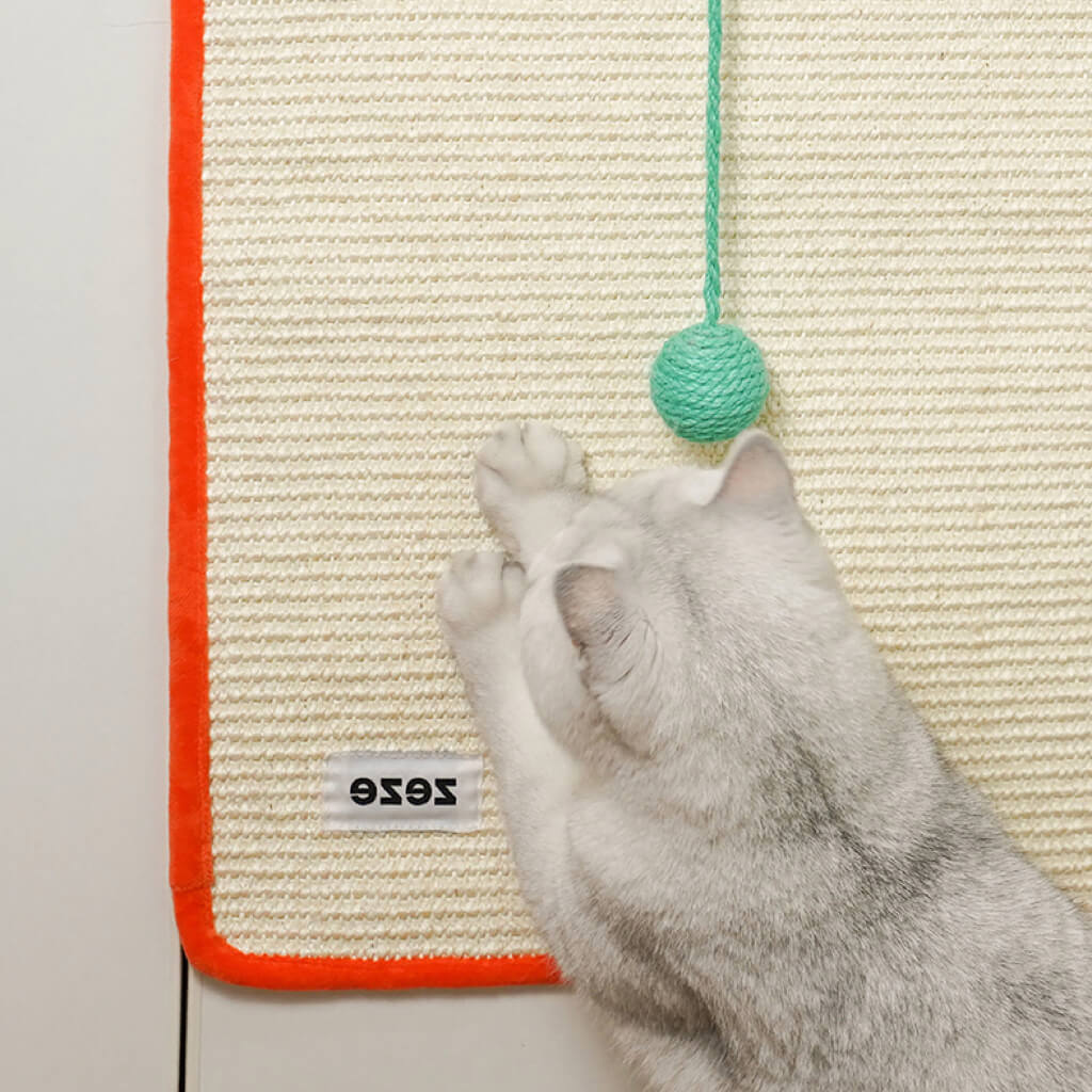Cat scratching the Dopamine-Style Cat Sisal Scratching Mat orange and light green mounted on a wall.