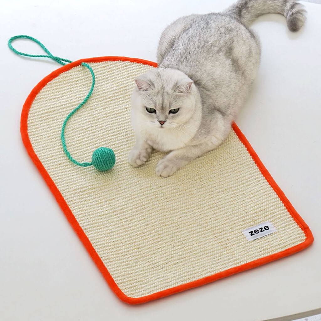 Cat lounging on Dopamine-Style Cat Sisal Scratching Mat with orange border and green pom-pom.