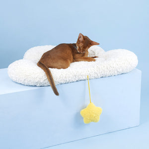Cat grooming itself while sitting on the Soft Cloud Pet Bed, with dangling yellow star toy.