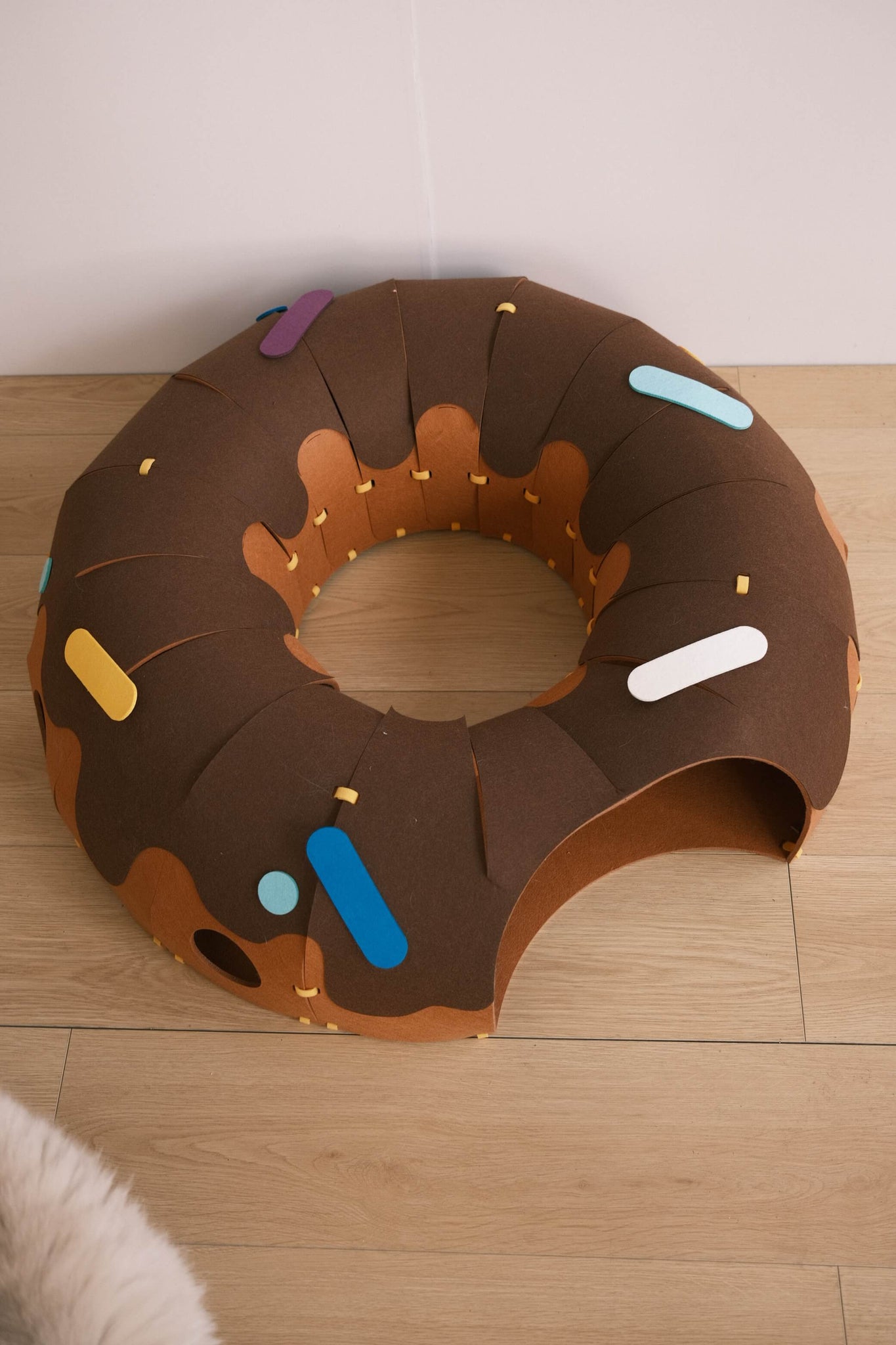 Top view of the Donut Design Cat Hideaway & Tunnel Toy placed on a wooden floor.