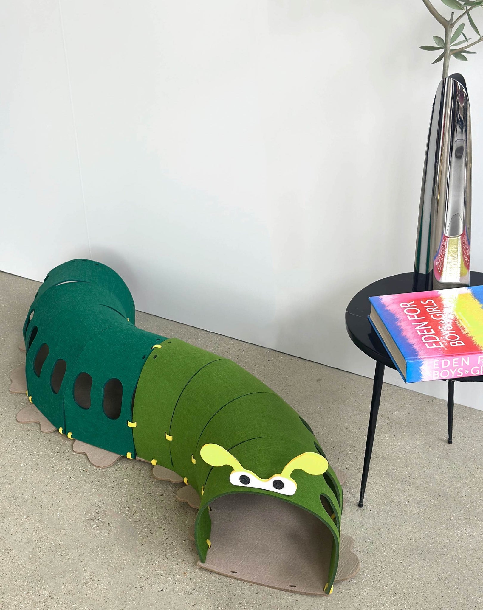 Design Cat Felt Tunnel Toy set up in a stylish modern interior with a book nearby.
