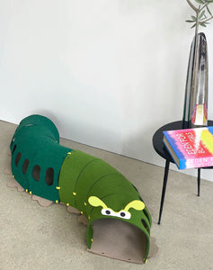 Design Cat Felt Tunnel Toy set up in a stylish modern interior with a book nearby.