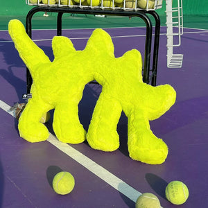Fluo Green Boom Boom Cat Cushion on a tennis court surrounded by tennis balls.