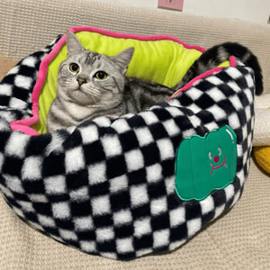Grey cat lounging in a black and white checker pattern pet bed with plush lime green fabric.