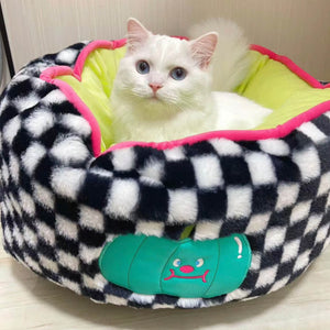 White fluffy cat resting in the soft and cozy black and white checker pattern bed with a pumpkin design on the side.