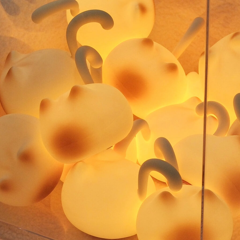 Pile of glowing cat silhouette tap lights — warm tone LEDs, portable and rechargeable night lamps.