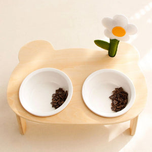 Stylish double pet bowl setup with a fabric flower and wooden stand, filled with pet food.