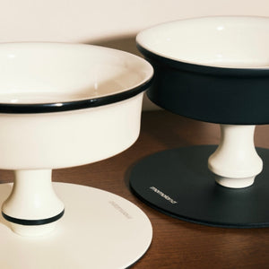 Close-up of Bamboo Island elevated ceramic pet bowls showing sleek black/white rims and pedestal base.