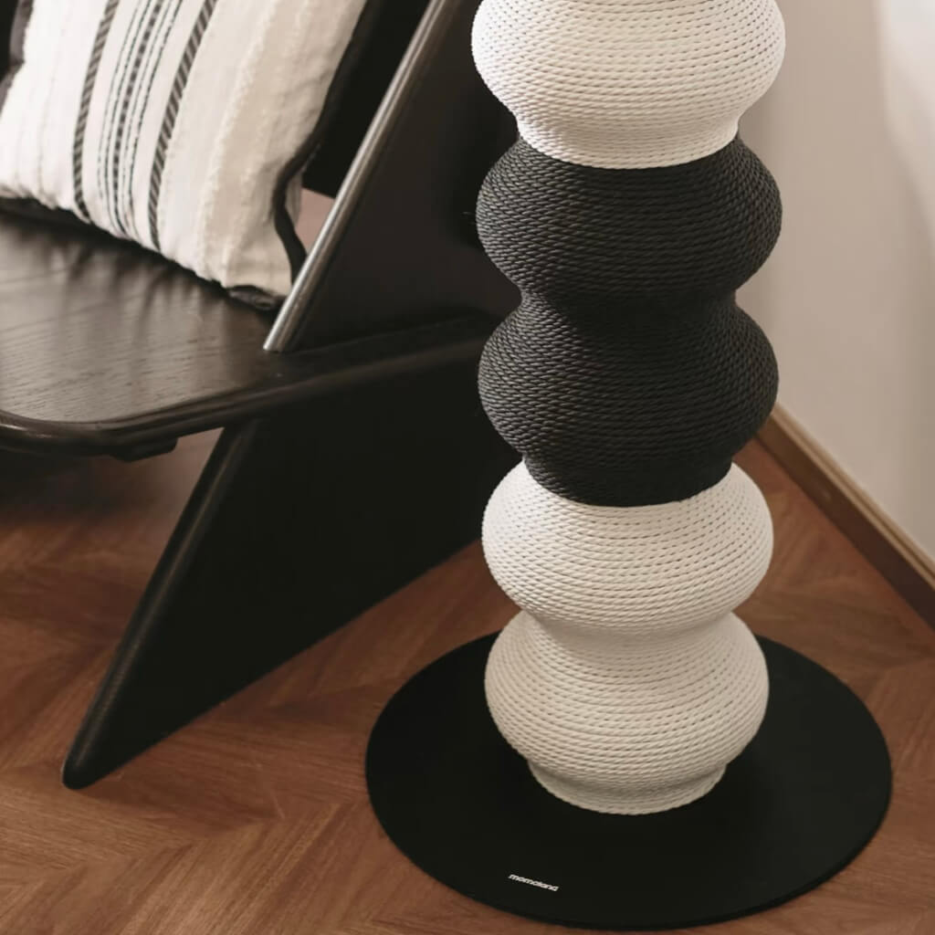 Close-up of Coral Cat Scratcher base next to chair; powder-coated round base and bicolor rope surface.