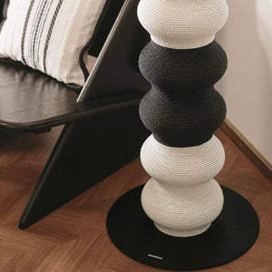 Close-up of Coral Cat Scratcher base next to chair; powder-coated round base and bicolor rope surface.