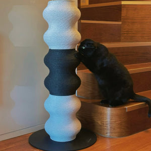Black cat working the middle section of the Coral Cat Scratcher by stairs — sturdy base, modern home.