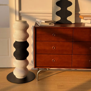 Coral Cat Scratcher, black & white wavy post beside mid-century dresser—modern décor, steel base, paper-vine rope.