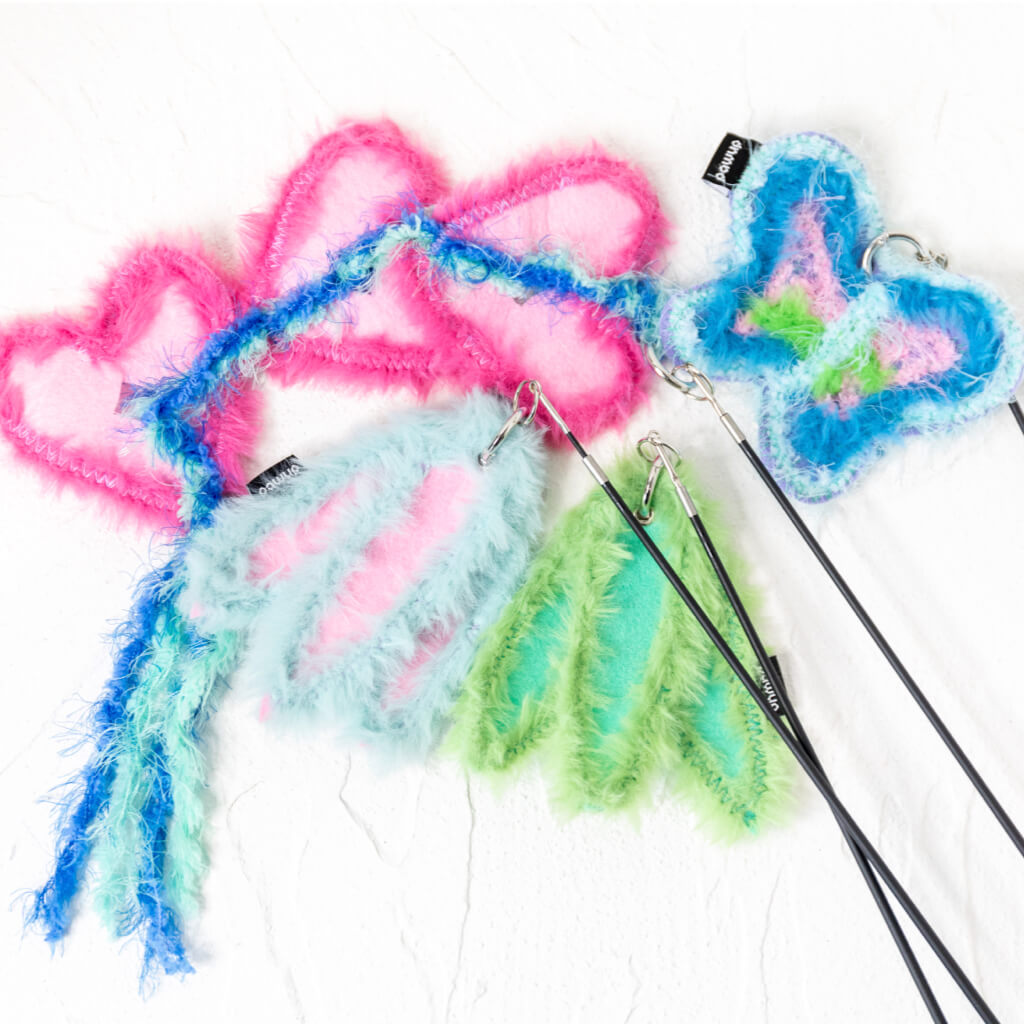 Assorted colorful attachments including hearts, leaves, and butterflies, laid out on a white background, demonstrating the playful variety of the bamboo cat teaser set.