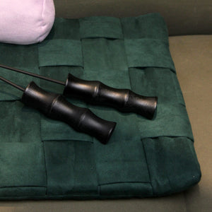 Close-up of bamboo-handled cat teasers lying on a dark green mat. The sleek black bamboo handle highlights the premium design.