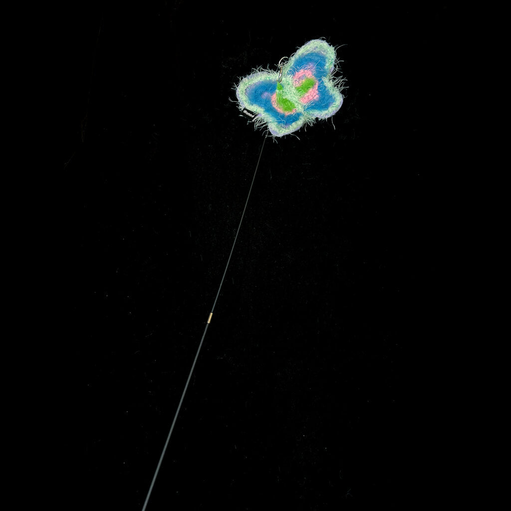 A blue butterfly attachment hanging from the bamboo cat teaser, set against a dark backdrop, ready for playful interaction with your feline.