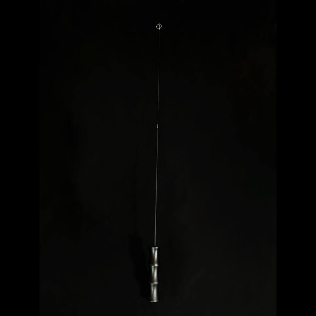 A minimalist bamboo teaser rod standing against a plain black background, highlighting the sleek and modern design of the product.