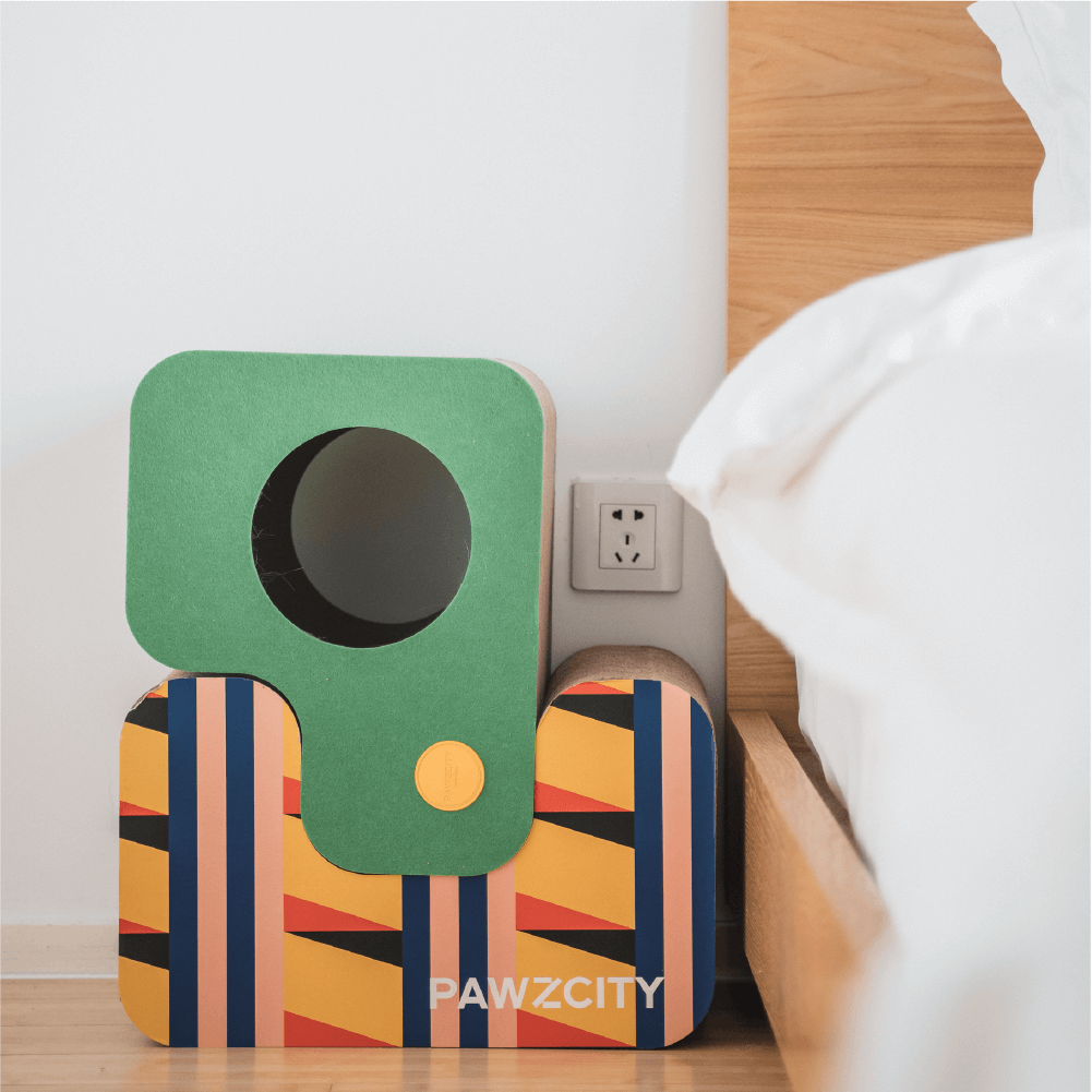 Close-up of modular cat scratcher in blue, white, and green with geometric patterns, placed next to a bedroom.
