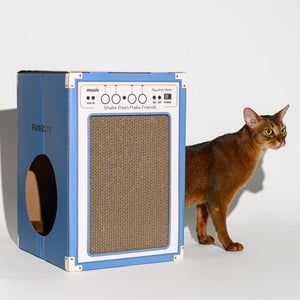 Side view of cat walking around the blue Pawzcity cat house designed like a speaker – interactive play and hideout.