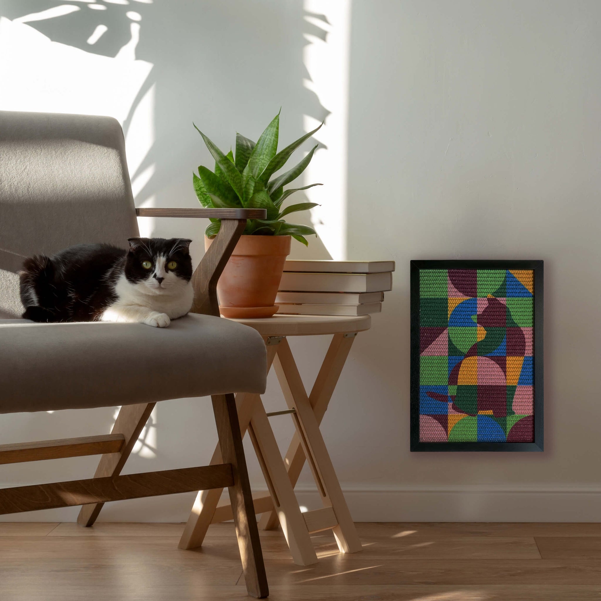 Cat lounging on a chair next to a colorful geometric cat-shaped scratcher, inspired by Paul Klee’s abstract art, adding a playful yet sophisticated touch to the living space.