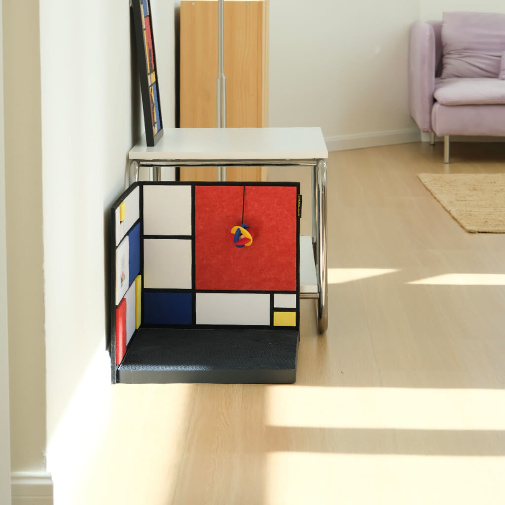 Slim L-shaped corner cat scratcher in narrow space — non-slip base with reversible color-block panels.