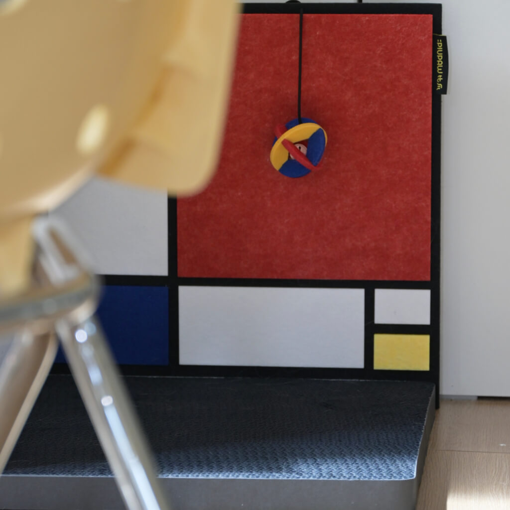 Close-up of hanging toy and textured non-slip base on Mondrian-inspired corner cat scratcher.