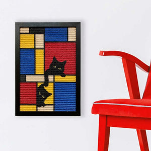 A black cat sitting on a white chair beside a framed Mondrian-inspired sisal scratcher featuring two playful black cat illustrations in bright colors.