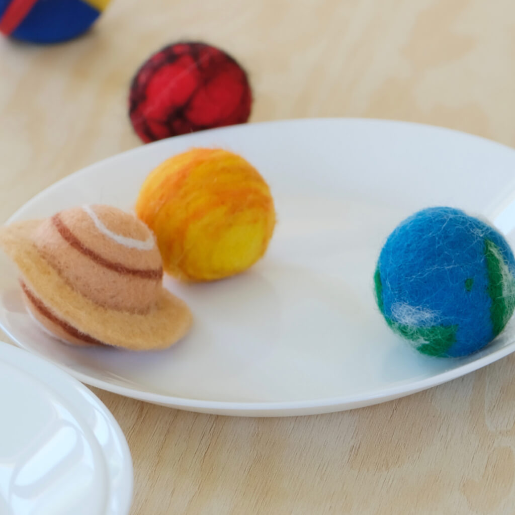 Saturn, Sun and Earth wool felt cat balls on a plate — lightweight planet toys.