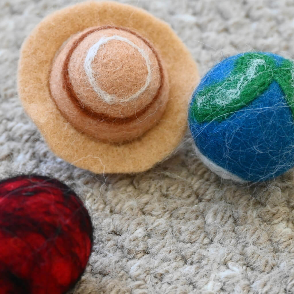 Close-up of Saturn and Earth felt balls — handmade wool cat toys for batting.