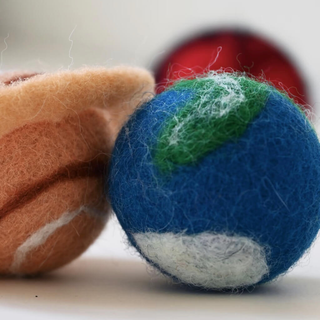 Macro detail of Earth and Saturn felt balls — soft 100% New Zealand wool.