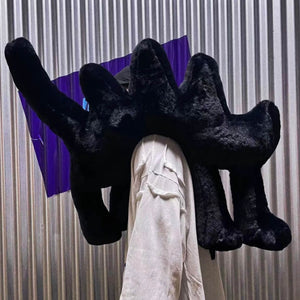 Model carrying Boom Boom Cat Cushion Black on their back against a metallic backdrop.
