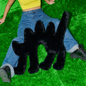 Person lying on the floor next to the Boom Boom Cat Cushion Black, on a green rug.