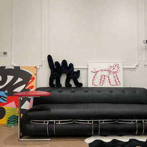 Boom Boom Cat Cushion Black styled on a modern black sofa with colorful artwork in the background.