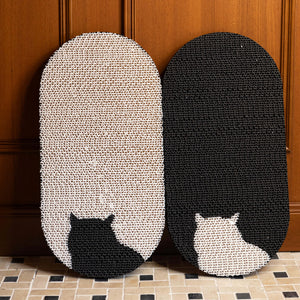 Close-up of black and white Cat Yin Yang Scratch Pads, leaning against a wooden surface, showcasing the unique cat silhouette design.
