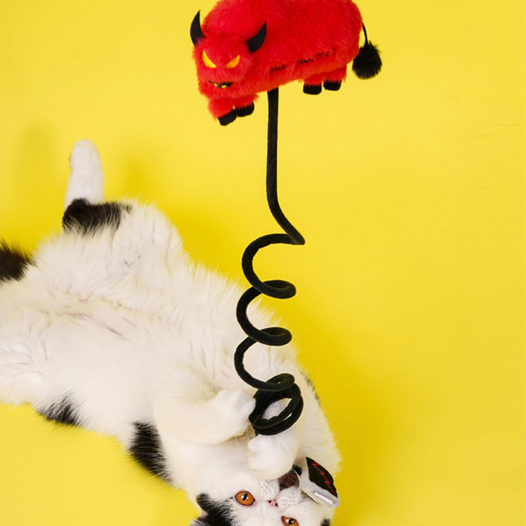 White and black cat playing with spiral cord of bull market themed cat toy