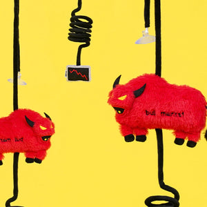 Two red plush bull toys hanging from spring cords with suction cups against yellow background.