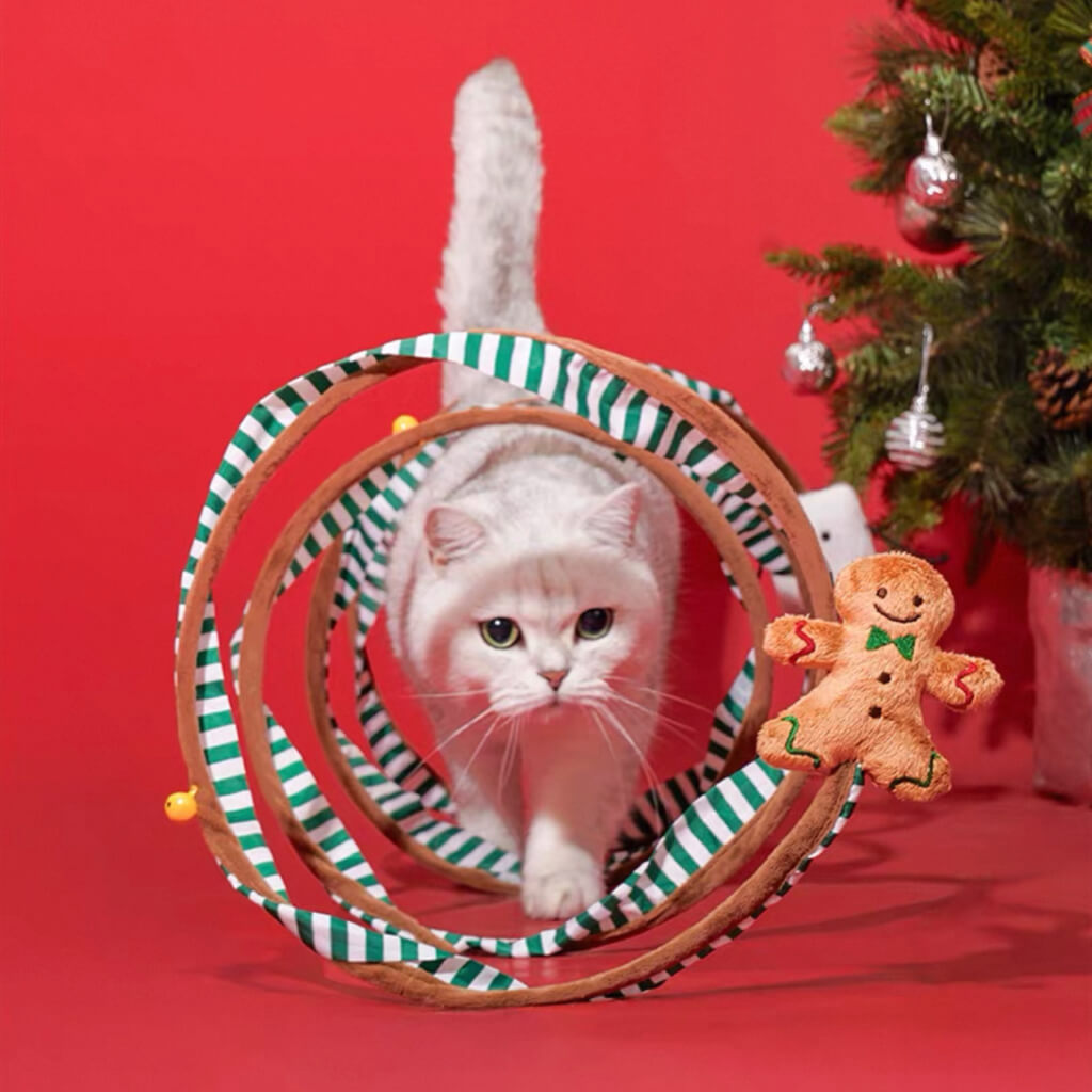 Cat walking through Christmas Bouncy Spiral Cat Tunnel — interactive spring coil toy with catnip topper and jingle bells.