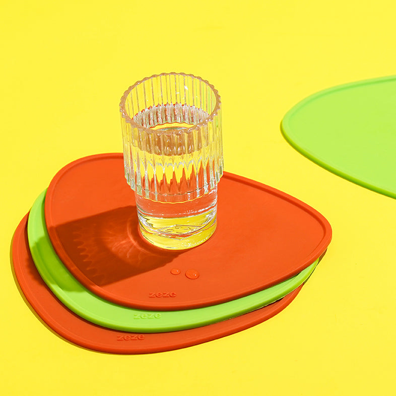 Close-up of stackable red and green silicone drink coasters.