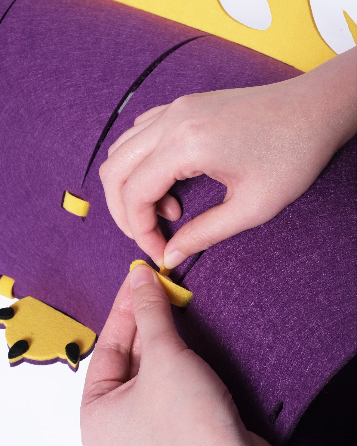 Close-up of hands assembling the felt dragon tunnel toy - Design Felt Cat Tunnel Assembly.