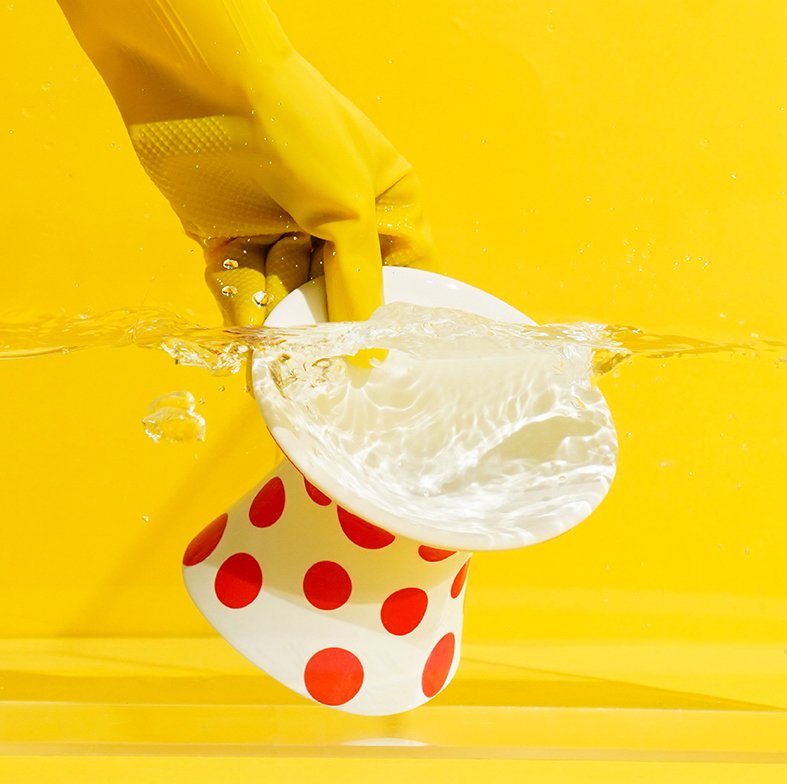 ZEZE Elevated Ceramic Bowl - Red Polka Dots being cleaned in water, showcasing easy maintenance.